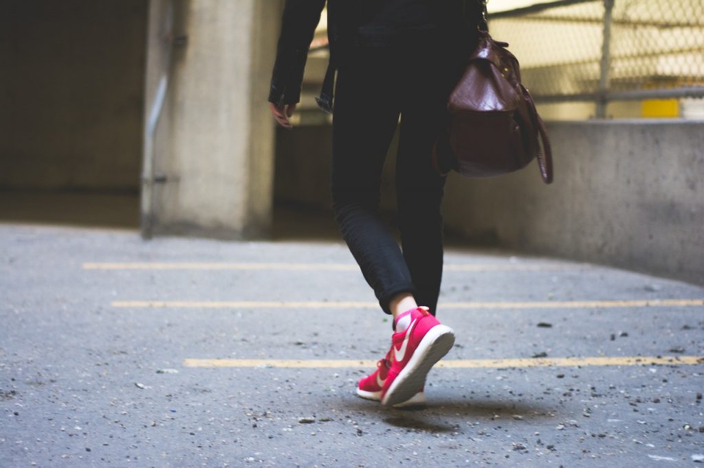 femme portant un blouson noir un pantalon noir et des baskets rouges